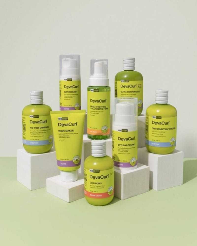 DevaCurl hair products arranged on white platforms against a light background.