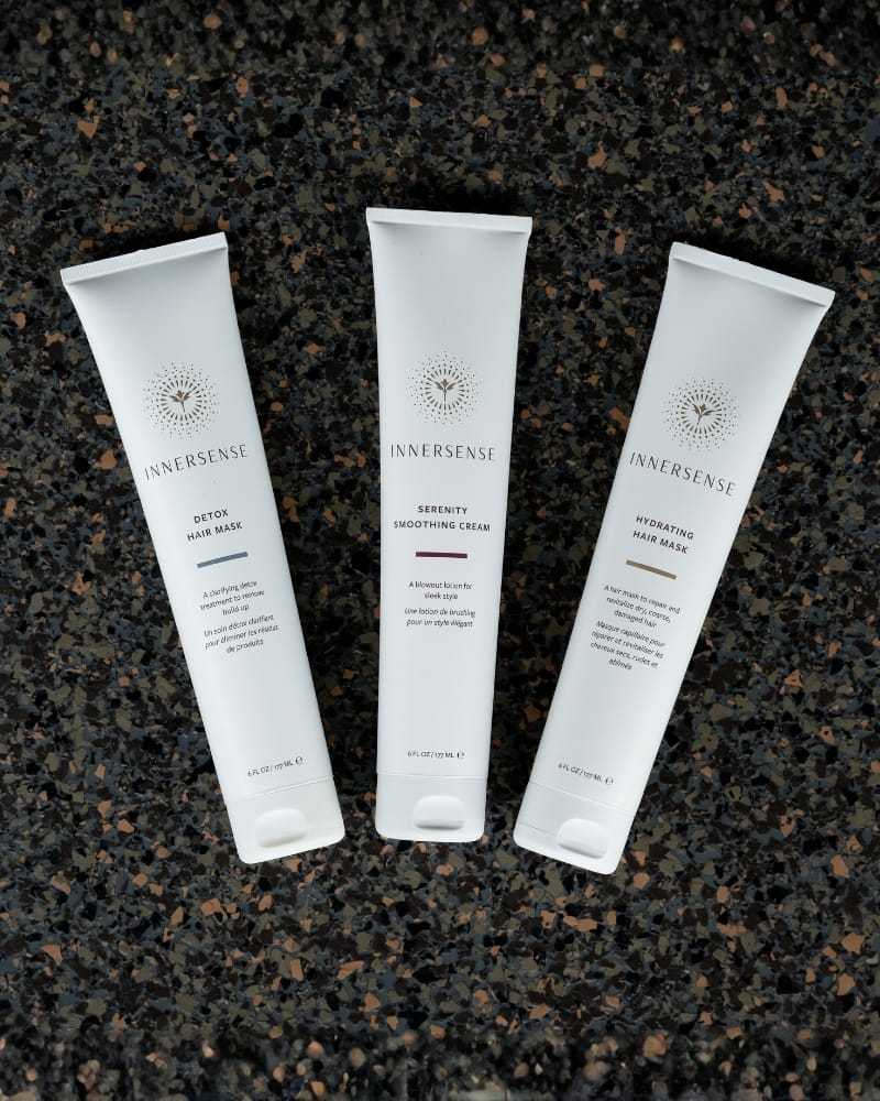 Three Innersense hair care products on a dark textured surface.