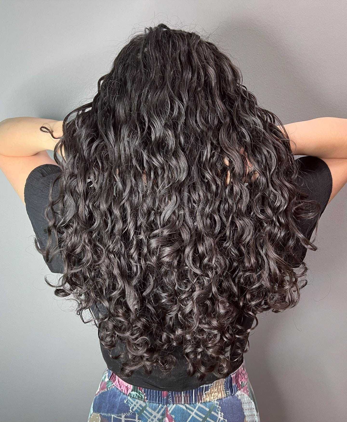 Curly-haired person facing away, showcasing voluminous, healthy curls.